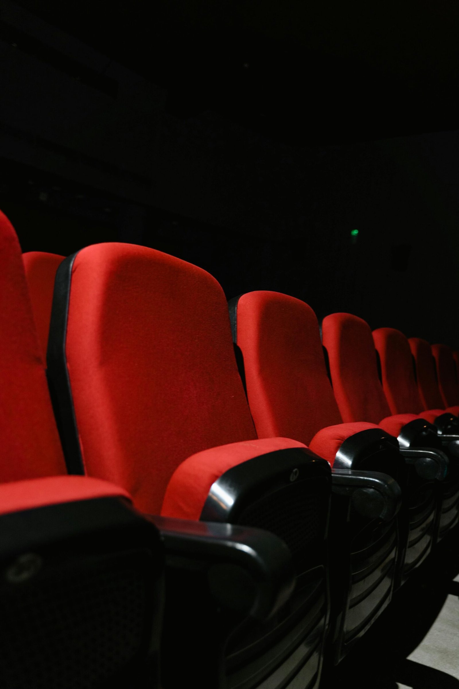 Rows of vibrant red seats in a dimly lit movie theater, awaiting an audience.